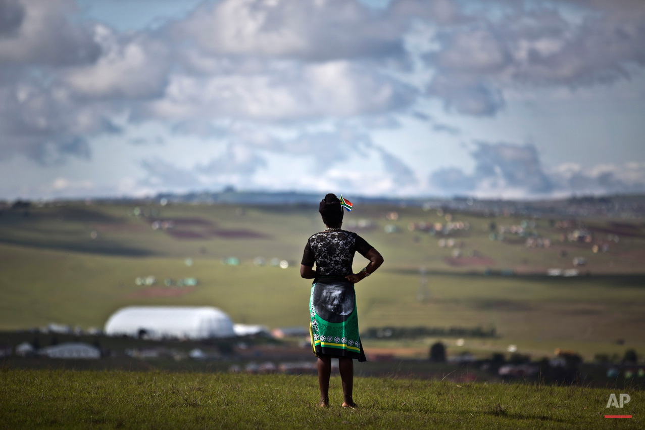  A mourner wearing a banner as a skirt showing the face of South African President Jacob Zuma observes the scene from a hilltop overlooking the burial site of Nelson Mandela in Qunu, South Africa Sunday, Dec. 15, 2013. (AP Photo/Ben Curtis) 