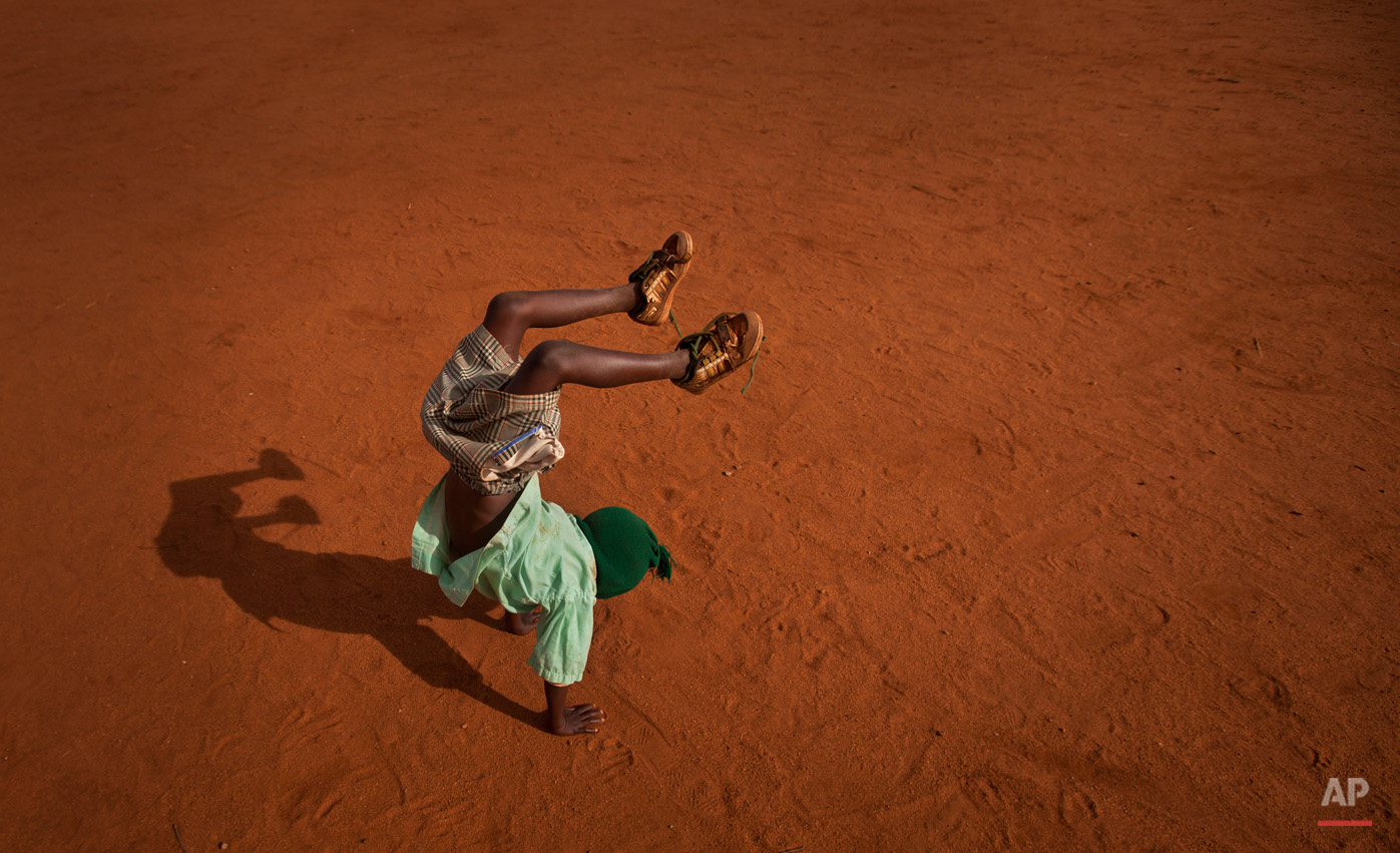  In this photo taken Wednesday, Nov. 21, 2012, a young schoolboy makes handstands during break in the yard of the Hot Courses Primary School, in the village of Nyumbani which caters to children who lost their parents to HIV, and grandparents who lost