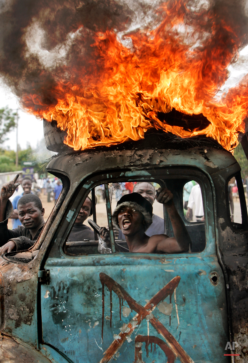  A Kenyan man sits in the cab of a destroyed truck used as a makeshift roadblock while a tyre burns on the roof, as he and others enforce the roadblock in Kisumu, Kenya, Tuesday, Jan. 29, 2008. The town of Kisumu is now almost completely ethnically c