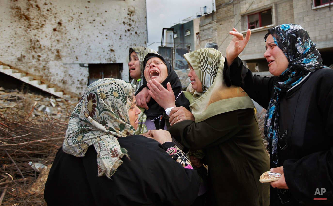  A Palestinian woman from the Suboh family weeps as she is comforted after learning the body of a releative was dug out of the rubble of a house destroyed in recent days in Israeli bombardment in Beit Lahiya, northern Gaza strip, Monday, Jan. 19, 200
