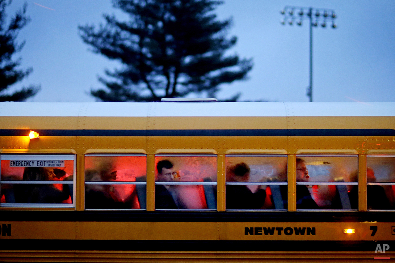  People arrive on a school bus at Newtown High School for a memorial vigil attended by President Barack Obama for the victims of the Sandy Hook Elementary School shooting, Sunday, Dec. 16, 2012, in Newtown, Conn. A gunman walked into Sandy Hook Eleme