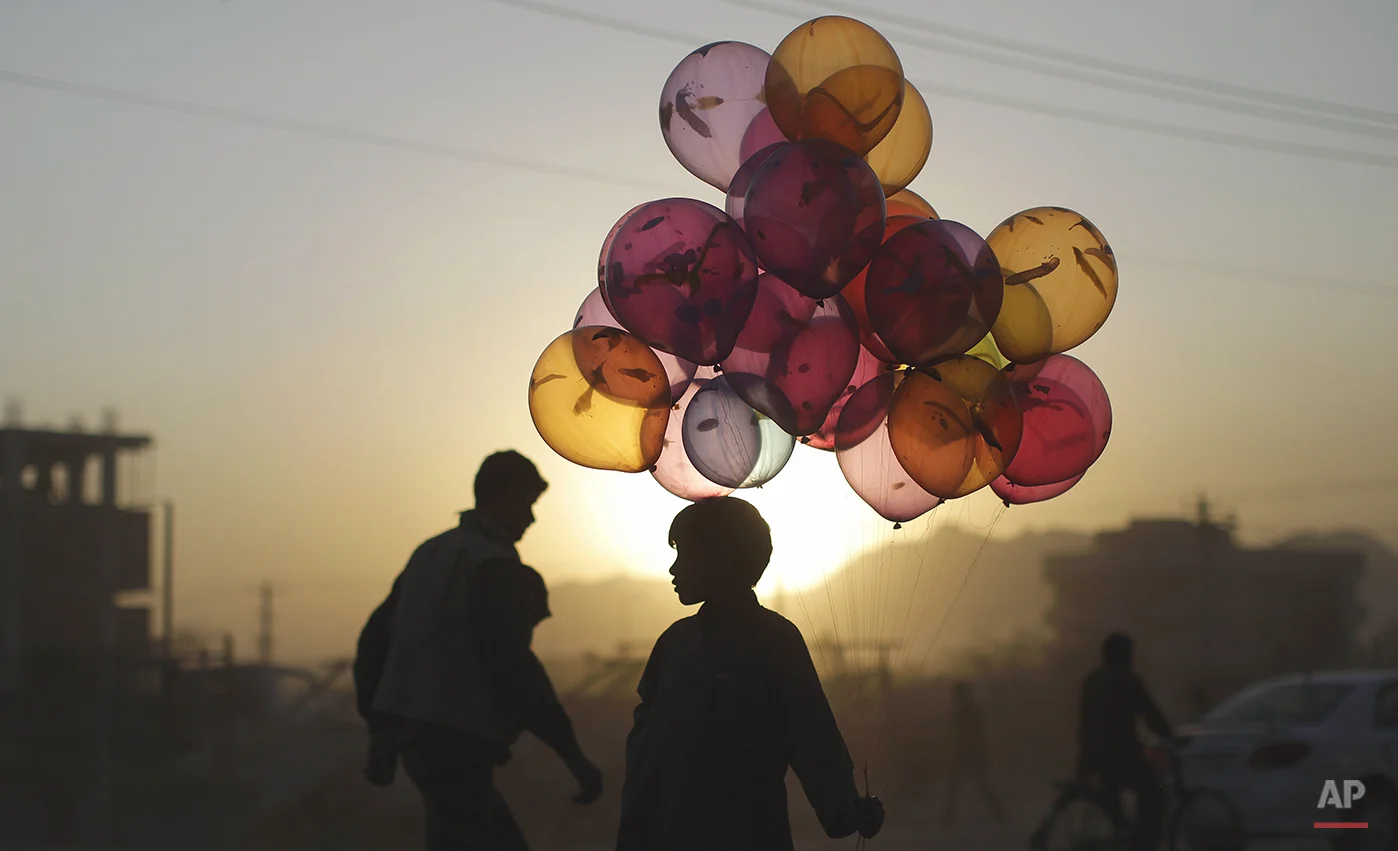 Afghan boy Mahfouz Bahbah, 12, stands on a roadside hoping to sell his balloons during sunset in Kabul, Afghanistan, Tuesday, Oct. 18, 2011. (AP Photo/Muhammed Muheisen)