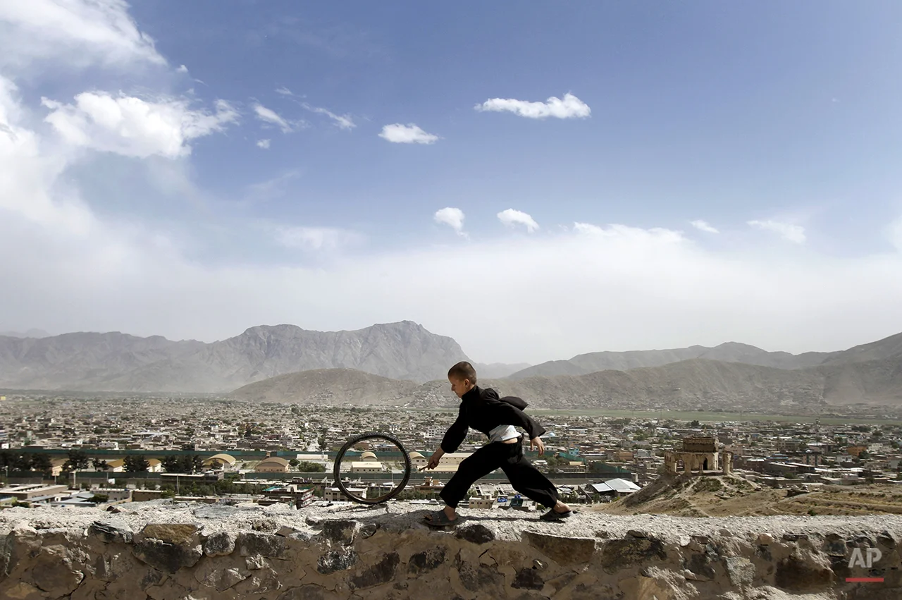 An Afghan boy pushes a wheel on the Naderkhan hill in Kabul, Afghanistan, Wednesday, May, 30, 2012. (AP Photo/ Ahmad Jamshid)