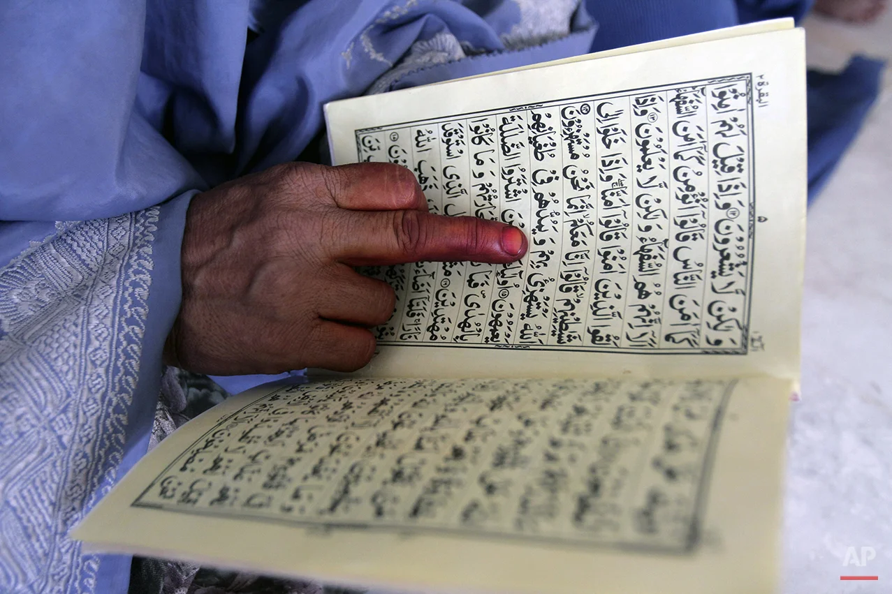 An Afghan woman learns to read Quran, Islam's holy book, at a local madrassa, or seminary, in Jalalabad, east of Kabul, Afghanistan, Tuesday, June 11, 2013. Islamic seminaries in Afghanistan are generally considered a source of education for poor families and children whose families could not afford expensive fees of formal schools. (AP Photo/Rahmat Gul)