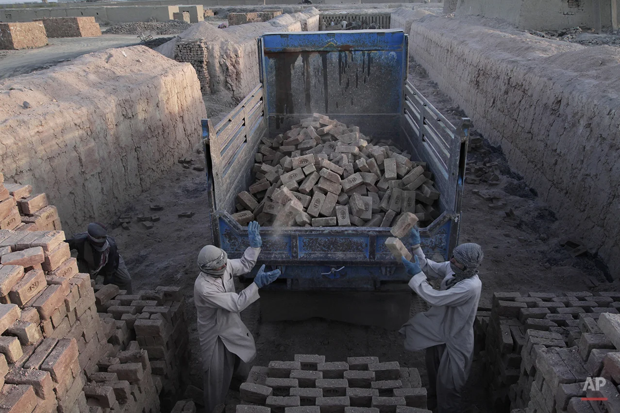 Mohammed Osman, 28, center, and Mohammad Anwar, 25, throw bricks onto a truck at a brick factory on the outskirts of Kabul, Afghanistan, Sunday, Oct. 27, 2013. Men generally work for 12 hours a day, six days a week, and make about 557.980 Afghani ($10) per day. (AP Photo/Rahmat Gul)