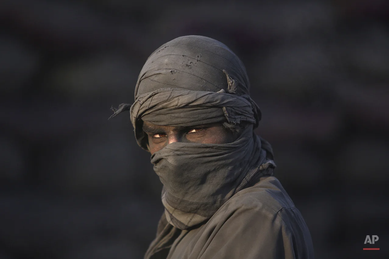 An Afghan laborer pauses as he works at a charcoal shop on the outskirts of Kabul, Afghanistan, Wednesday, Nov. 26, 2014. In the winter, prices of wood and charcoal rise among all other necessities for Afghans. (AP Photo/Rahmat Gul)