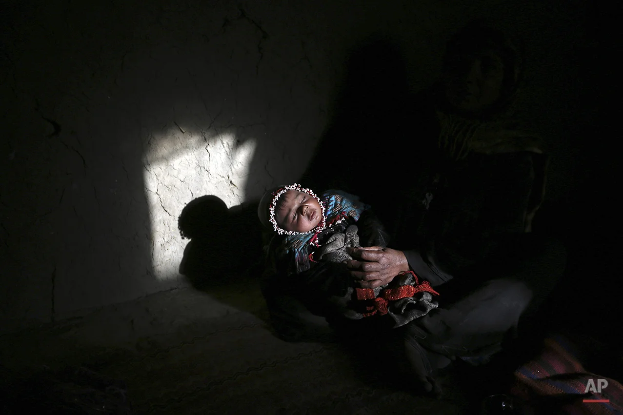 Sana, a 30-day-old Afghan girl, sleeps on her grandmother's lap in her home on the outskirts of Kabul, Afghanistan, Friday, Dec. 5, 2014. (AP Photo/Rahmat Gul)