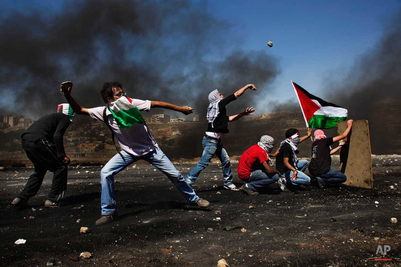  Masked Palestinians hurl stones at Israeli troops, not seen, during clashes outside the Ofer military prison, near the West Bank city of Ramallah, Tuesday, May 15, 2012 during the 64th anniversary of "Nakba", Arabic for catastrophe, the term used to