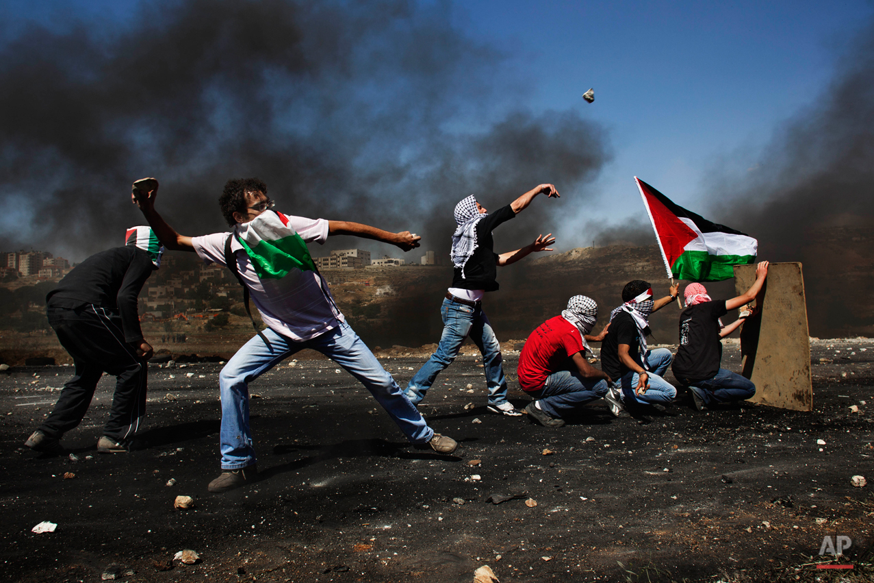 Masked Palestinians hurl stones at Israeli troops, not seen, during clashes outside the Ofer military prison, near the West Bank city of Ramallah, Tuesday, May 15, 2012 during the 64th anniversary of "Nakba", Arabic for catastrophe, the term used to mark the events leading to Israel's founding in 1948. Hundreds of thousands of Palestinians fled or were forced from their villages during the war over Israel's 1948 creation, an event they commemorate every year as their "Nakba". (AP Photo/Bernat Armangue)