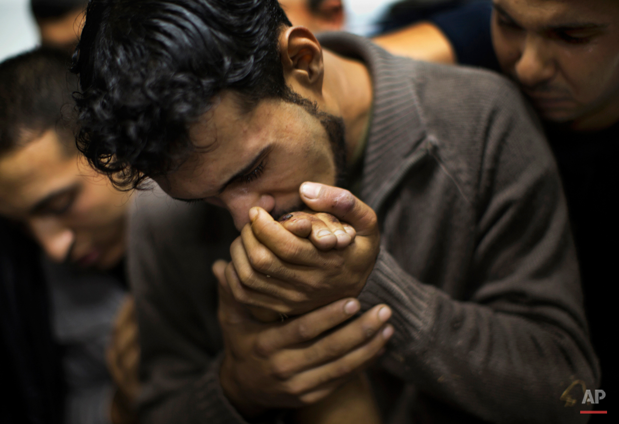  FILE - In this Nov. 18, 2012 file photo, a Palestinian man kisses the hand of a dead relative in the morgue of Shifa Hospital in Gaza City. This photo was one in a series of images by Associated Press photographer Bernat Armangue that won the first 