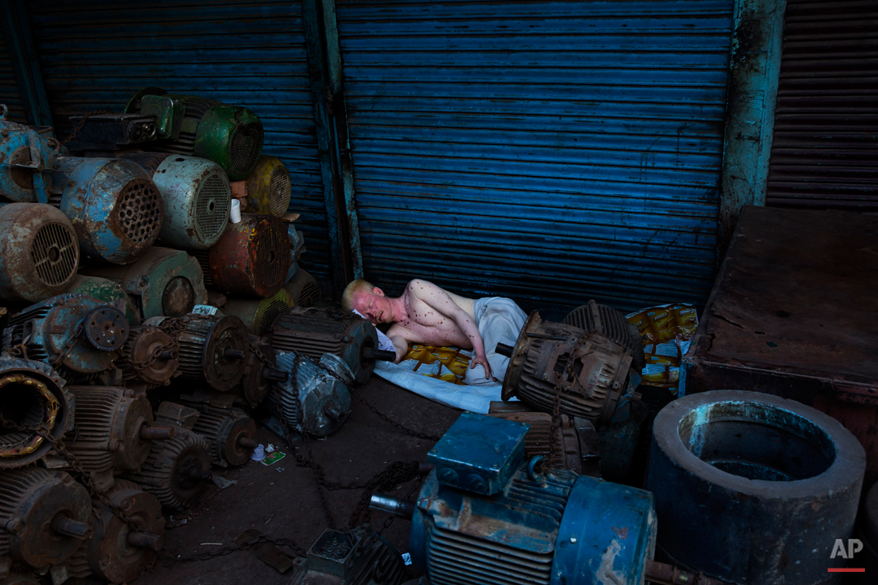  An albino man sleeps surrounded of piles of equipment in New Delhi, India, Tuesday, Aug. 26, 2014. Many laborers in the Indian capital have no permanent residence and are forced to sleep in the streets. (AP Photo/Bernat Armangue) 