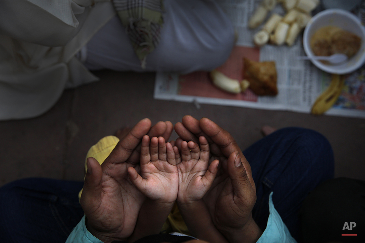  An Indian Muslim father holds the hands of his daughter in his palms and prays before  breaking fast on the first day of holy month Ramadan at the Jama Mosque in New Delhi, India, Monday, June 30, 2014. During this month the world's estimated 1.6 bi