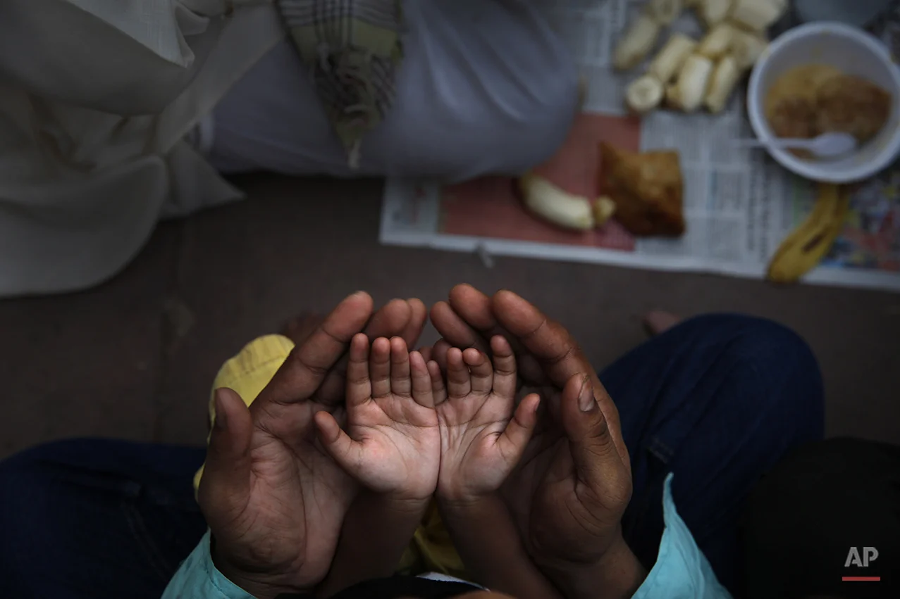 An Indian Muslim father holds the hands of his daughter in his palms and prays before breaking fast on the first day of holy month Ramadan at the Jama Mosque in New Delhi, India, Monday, June 30, 2014. During this month the world's estimated 1.6 billion Muslims will abstain from food, drink and other pleasures from sunrise to sunset. (AP Photo /Manish Swarup)