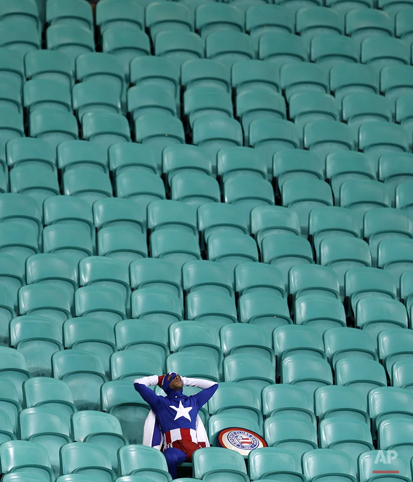 A lone USA supporter dressed as 'Captain America' sits in the stands after Belgium defeated the USA 2-1 in extra time to advance to the quarterfinals during the World Cup round of 16 soccer match between Belgium and the USA at the Arena Fonte Nova in Salvador, Brazil, Tuesday, July 1, 2014. (AP Photo/Natacha Pisarenko)
