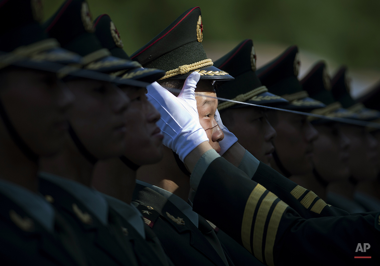  A Chinese People's Liberation Army soldier adjusts a hat of a member of a guard of honor as they prepare for a welcome ceremony for visiting Italian Prime Minister Matteo Renzi held outside the Great Hall of the People in Beijing, China Wednesday, J