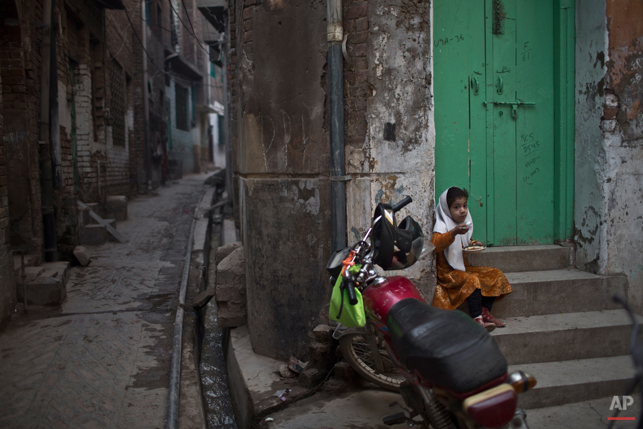  A girl, eats by the doorway of her home, near the house of Pakistani student Nasrullah Abdullah, 17, who was killed in last Tuesday's Taliban attack on a military-run school, in Peshawar, Pakistan, Thursday, Dec. 18, 2014. The Taliban massacre that 