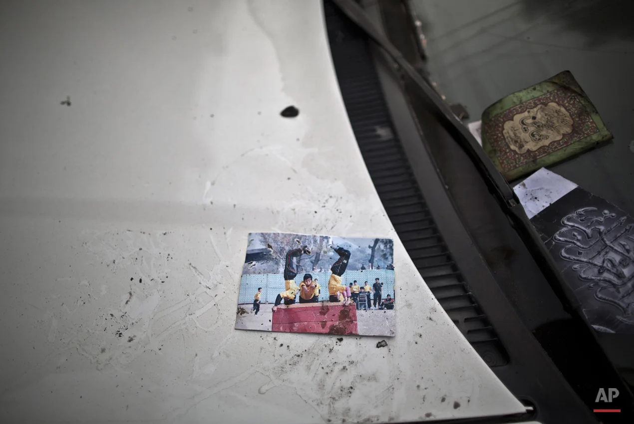 A picture showing schoolchildren playing is left on a car, inside the Army Public School attacked last Tuesday by Taliban gunmen, in Peshawar, Pakistan, Thursday, Dec. 18, 2014. The Taliban massacre that killed more than 140 people, mostly children, at a military-run school in northwestern Pakistan left a scene of heart-wrenching devastation, pools of blood and young lives snuffed out as the nation mourned and mass funerals for the victims got underway. (AP Photo/Muhammed Muheisen)