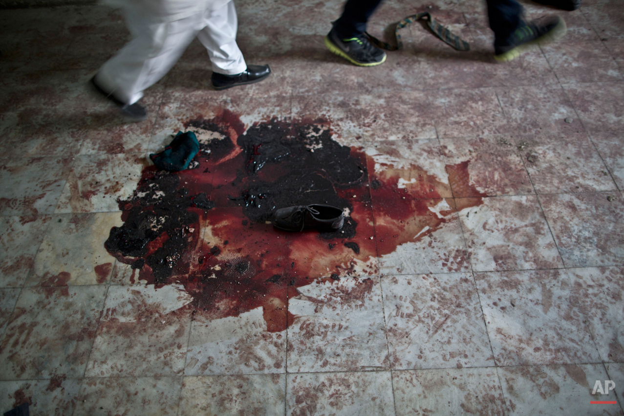  Pakistani men walk past a shoe and blood inside the Army Public School, attacked Tuesday by Taliban gunmen in Peshawar, Pakistan, Thursday, Dec. 18, 2014. The Taliban massacre that killed more than 140 people, mostly children, at the military-run sc