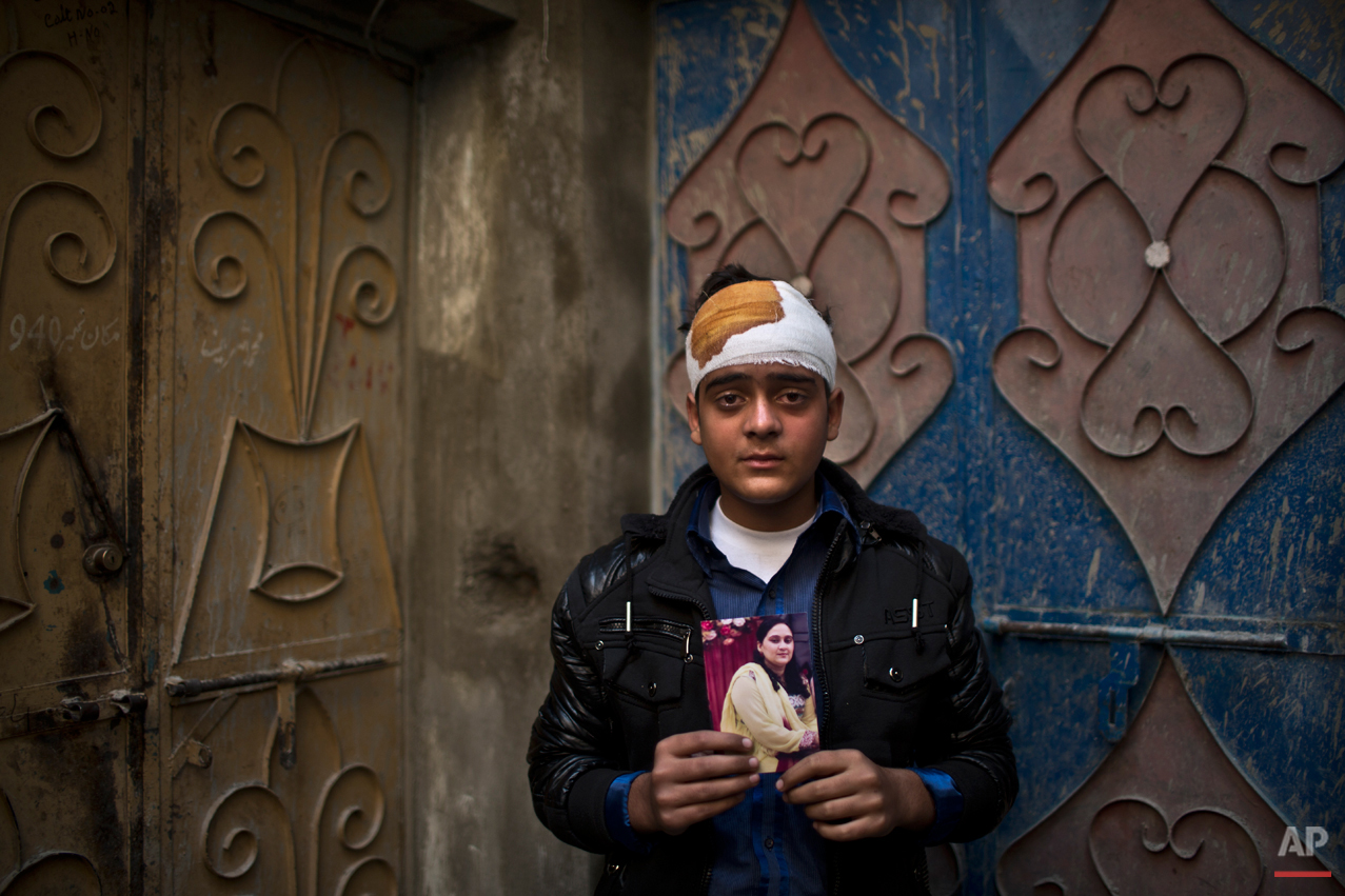  Pakistani student, Mohammad Baqair, who survived last Tuesday's Taliban attack on a military-run school and was slightly injured, poses for a picture holding a photograph of his mother a victim of the attack, who was a teacher at the school, at his 