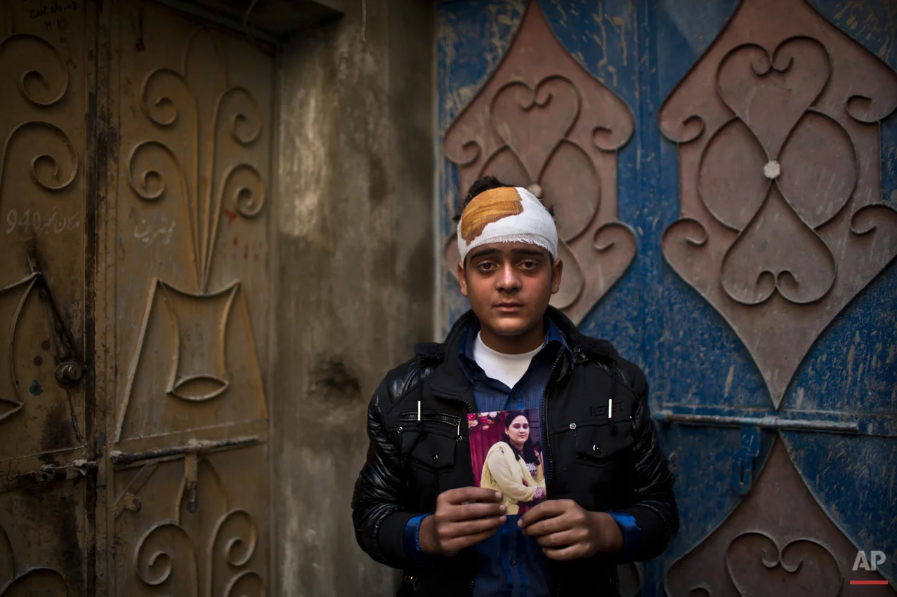 Pakistani student, Mohammad Baqair, who survived last Tuesday's Taliban attack on a military-run school and was slightly injured, poses for a picture holding a photograph of his mother a victim of the attack, who was a teacher at the school, at his home, in Peshawar, Pakistan, Thursday, Dec. 18, 2014. The Taliban massacre that killed more than 140 people, mostly children, at a military-run school in northwestern Pakistan left a scene of heart-wrenching devastation, pools of blood and young lives snuffed out as the nation mourned and mass funerals for the victims got underway. (AP Photo/Muhammed Muheisen)