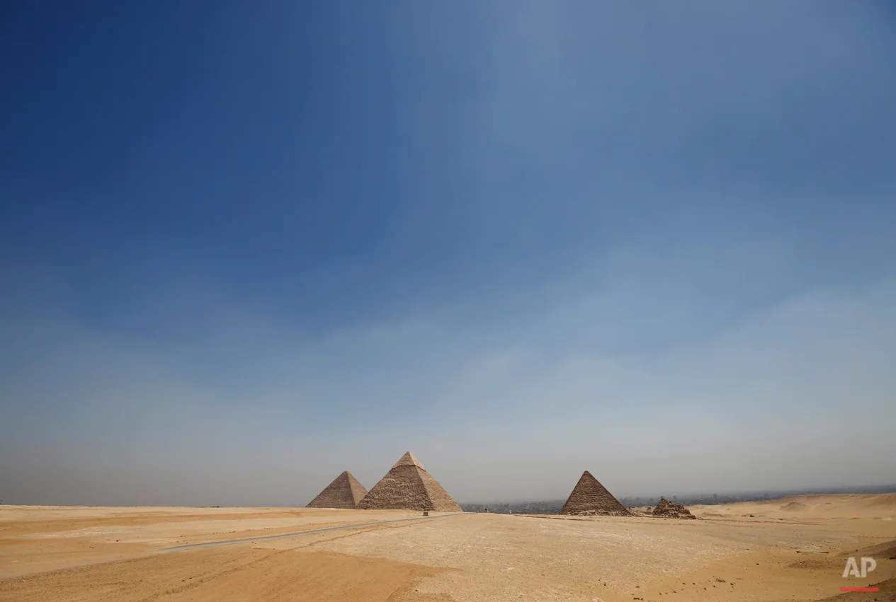 In this Saturday, Sept. 7, 2013 photo, the Giza Pyramids stand out from the desert on the horizon, near Cairo, Egypt. Before the 2011 revolution that started Egypt's political roller coaster, sites like the pyramids were often overcrowded with visitors and vendors, but after a summer of coup, protests and massacres, most tourist attractions are virtually deserted to the point of being serene. (AP Photo/Lefteris Pitarakis)