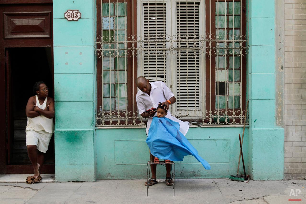  Barber Orlando Gonzalez cuts the hair of young client Maikol as Gonzalez' sister Cilia looks on along a sidewalk in Havana, Cuba, Wednesday Oct. 6, 2010. (AP Photo/Franklin Reyes) 