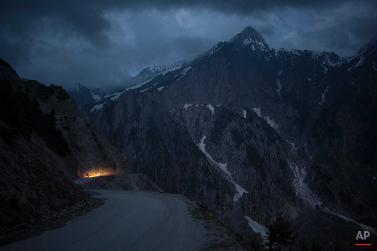  In this Monday, June 30, 2014 photo, a car moves on a serpentine road past snow-capped peaks near Zoji La in Indian-Kashmir, India. Many Tibetans say that being in the mountains make them miss their homeland. (AP Photo/Tsering Topgyal) 