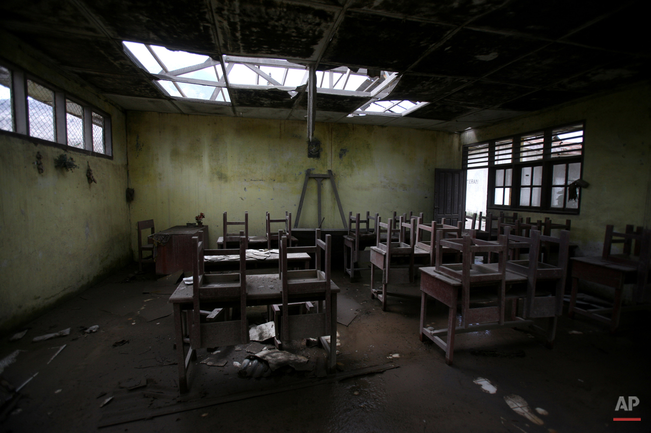  In this Oct 17, 2014, photo, chairs rest on tables in an empty classroom at an elementary school in the abandoned village of Simacem, North Sumatra, Indonesia. The village was abandoned after its people were evacuated following the eruption of Mount