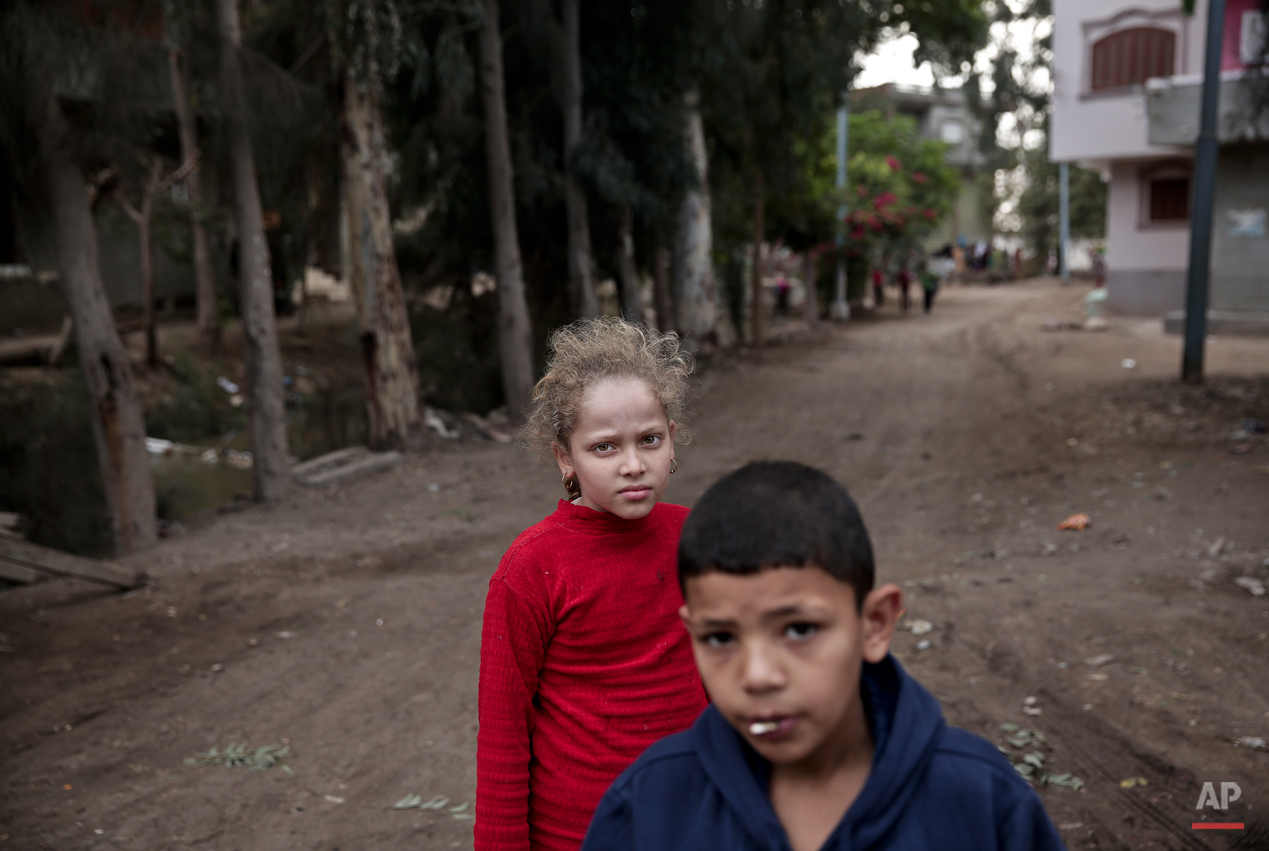  In this Wednesday, Nov. 5, 2014 photo, Egyptian school children walk on a street, near the home of 13-year-old Sohair el-Batea who died undergoing the procedure of female genital mutilation performed by Dr. Raslan Fadl, in Dierb Biqtaris village, on