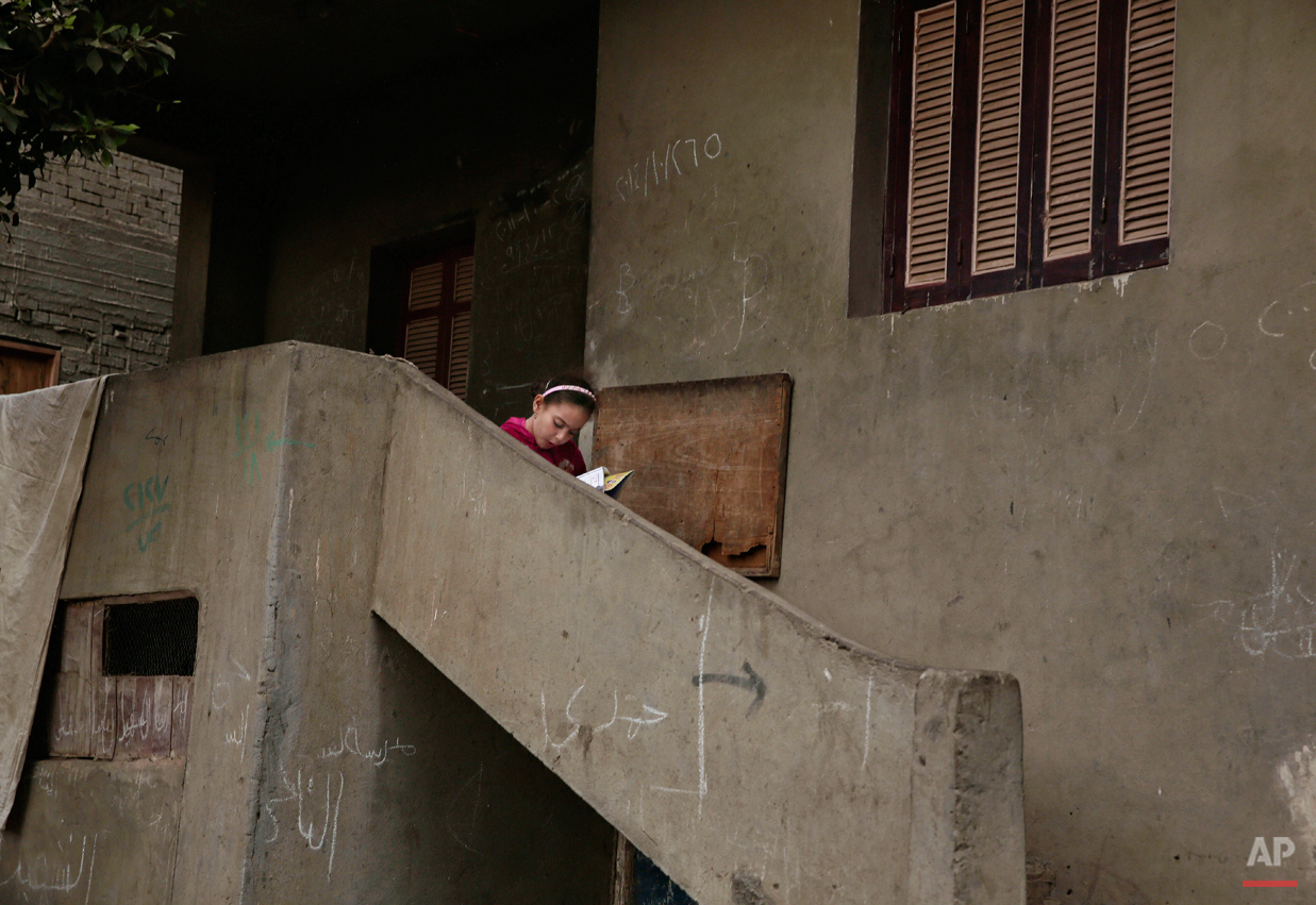  In this Wednesday, Nov. 5, 2014 photo, an Egyptian girl reads a book on a stairway, near the home of 13-year-old Sohair el-Batea who died undergoing the procedure of female genital mutilation performed by Dr. Raslan Fadl, in Dierb Biqtaris village, 