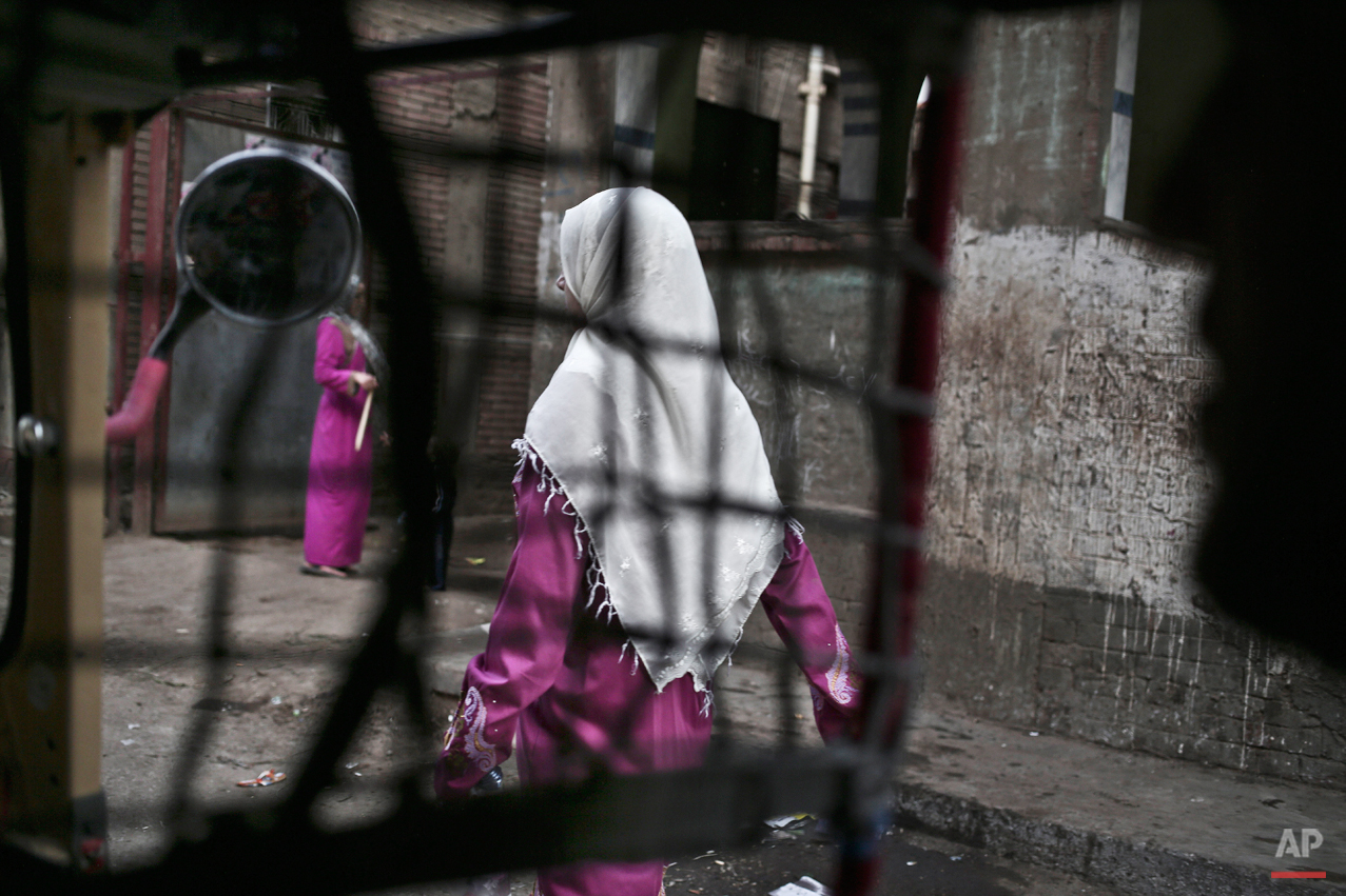  In this Wednesday, Nov. 5, 2014 photo, an Egyptian woman seen from a motorized rickshaw walks on a street, near the home of 13-year-old Sohair el-Batea who died undergoing the procedure of female genital mutilation committed by Dr. Raslan Fadl, in D