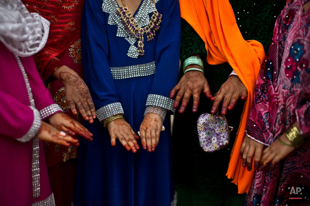 Afghan refugee children, display their hands that decorated with bangles and painted with henna paste as they celebrate the Muslim holiday of Eid al-Adha, or Feast of Sacrifice, on the outskirts of Islamabad, Pakistan, Monday, Oct. 6, 2014. Muslims around the world celebrate the Eid to commemorate what Muslims believe was Prophet Abraham's willingness to sacrifice his son Ismail. Because the holiday follows the Muslim lunar calendar that depends on sightings of the moon, the holiday starts on Monday in Pakistan. (AP Photo/Muhammed Muheisen)