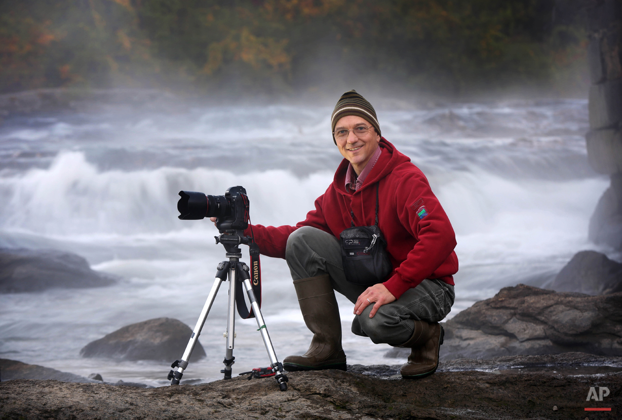  A.P. staff photographer Robert F. Bukaty poses while shooting a feature photo at the Royal River in Yarmouth, Maine, Monday, Oct. 6, 2014.  (AP Photo/Robert F. Bukaty) 