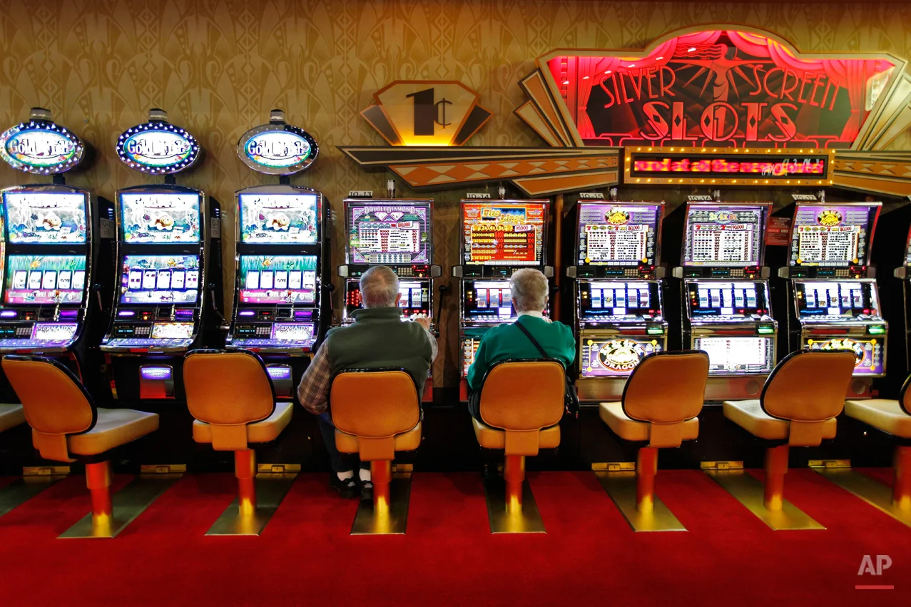 In this March 16, 2012 photo, a couple plays the slot machines at Hollywood Slots, Friday, in Bangor, Maine. The Legislature is considering bills to expand gambling operations in Maine for the Passamaquoddy tribe, veterans organizations and other groups. (AP Photo/Robert F. Bukaty)
