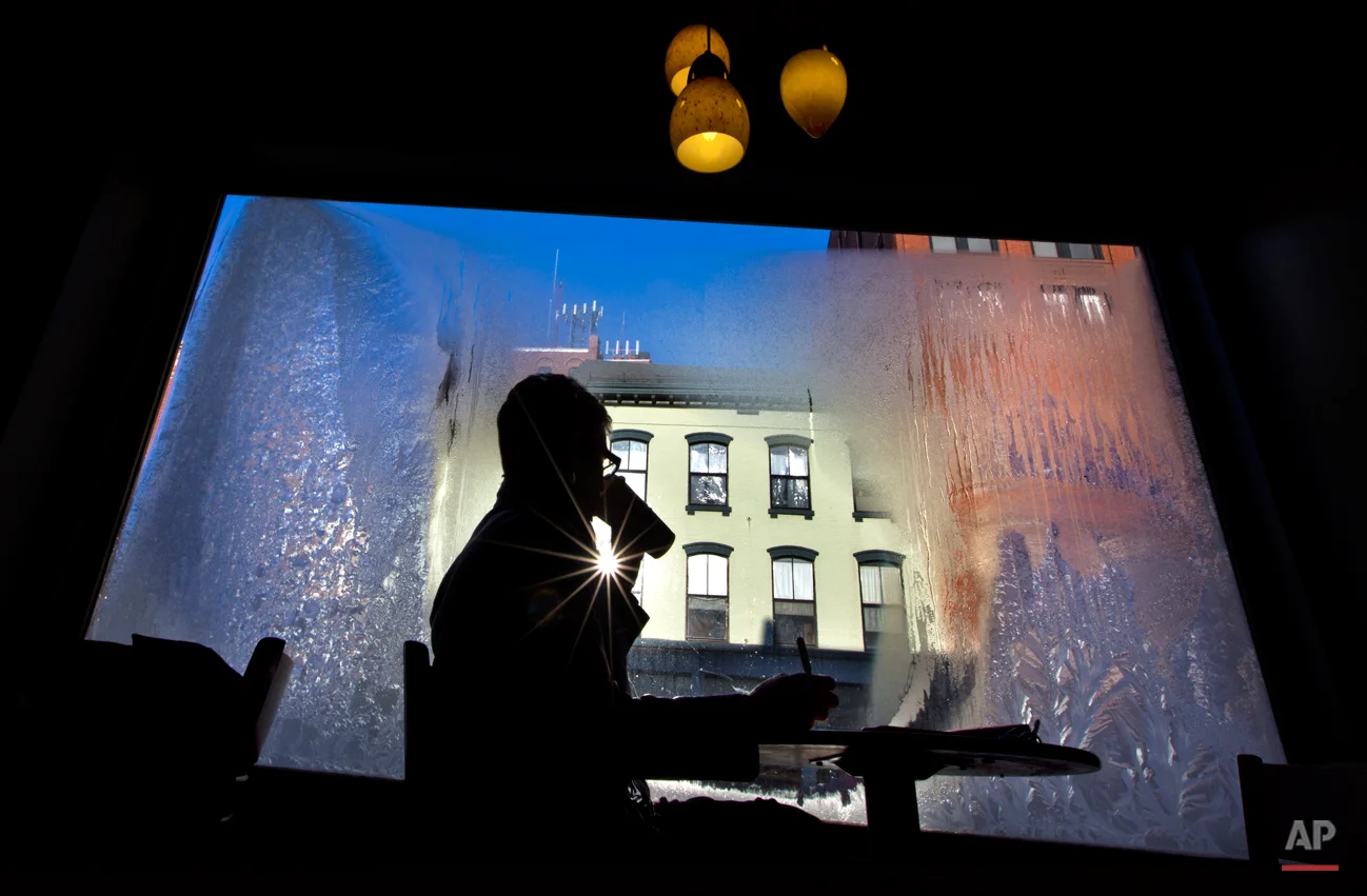 Erin Leighton sips a coffee while seated next to a frost-covered window at a coffee shop, Thursday, Jan. 24, 2013, in Portland, Maine. An arctic cold front with sub-zero temperatures continues to grip the region. (AP Photo/Robert F. Bukaty)