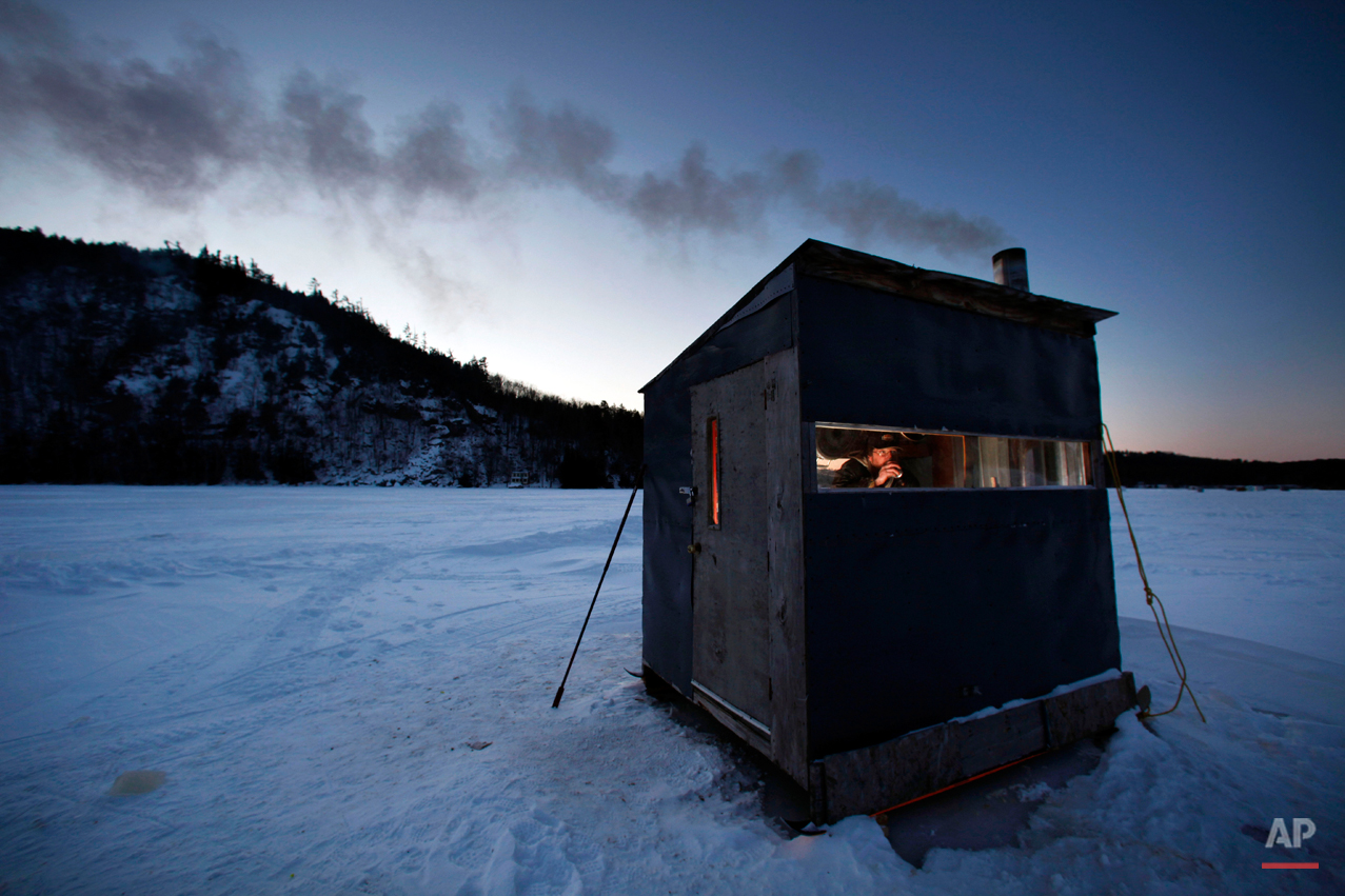  Tom Locklin, of Bethel, Maine, sips a beer as he looks out of his warm ice fishing shack on Christopher Lake where the temperature was 0 degrees at dusk, Thursday, Jan. 15, 2009, in Bryant Pond, Maine.  "This weather ain't bad" said Locklin, "but if