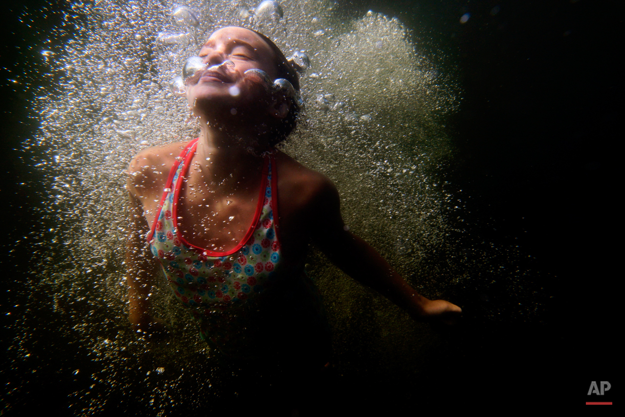  Kayla Raymond, 11, of Standish, Maine, surfaces through the bubbles after diving into Sabbathday Lake in New Gloucester, Maine, August 2011. (Photo by Robert F. Bukaty) 