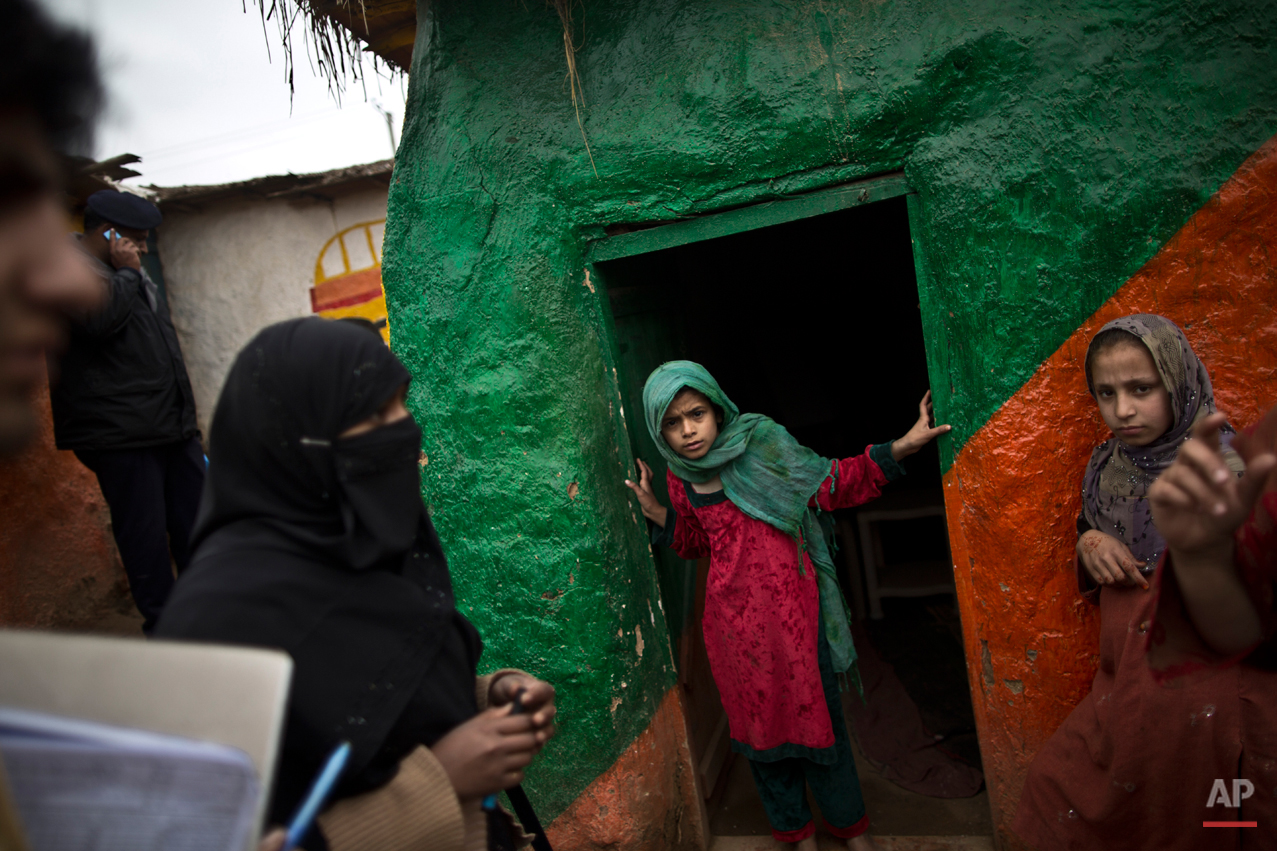  In This Monday, March 10, 2014, photo, a Pakistani health worker, left, checks with a teacher whether schoolchildren need a polio vaccine at a makeshift school on the outskirts of Islamabad, Pakistan. Malala Yousafzai's struggle for girls to be educ