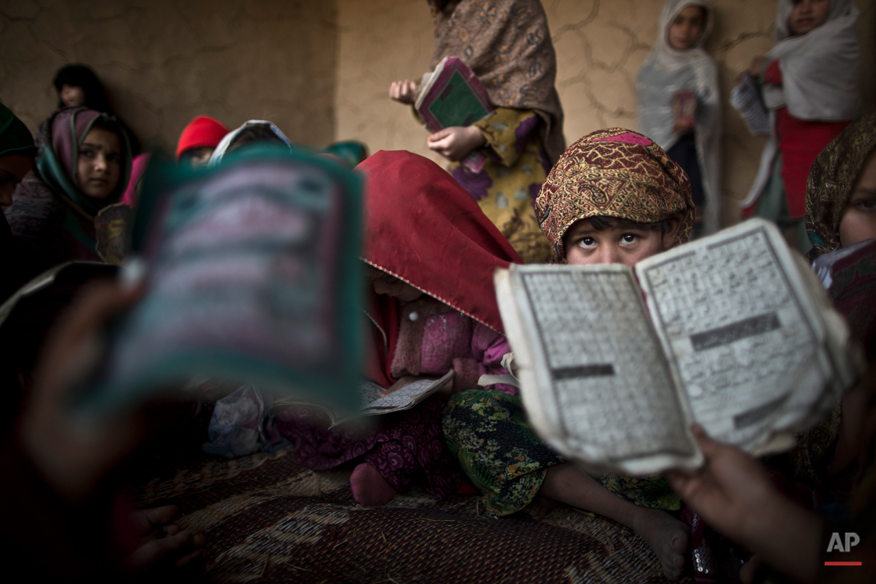  In this Tuesday, Jan. 28, 2014, photo, Pakistani children, whose families were displaced from Pakistan's tribal areas due to fighting between the Taliban and the army, hold booklets of Urdu alphabets and verses of the Quran, and repeat after their t