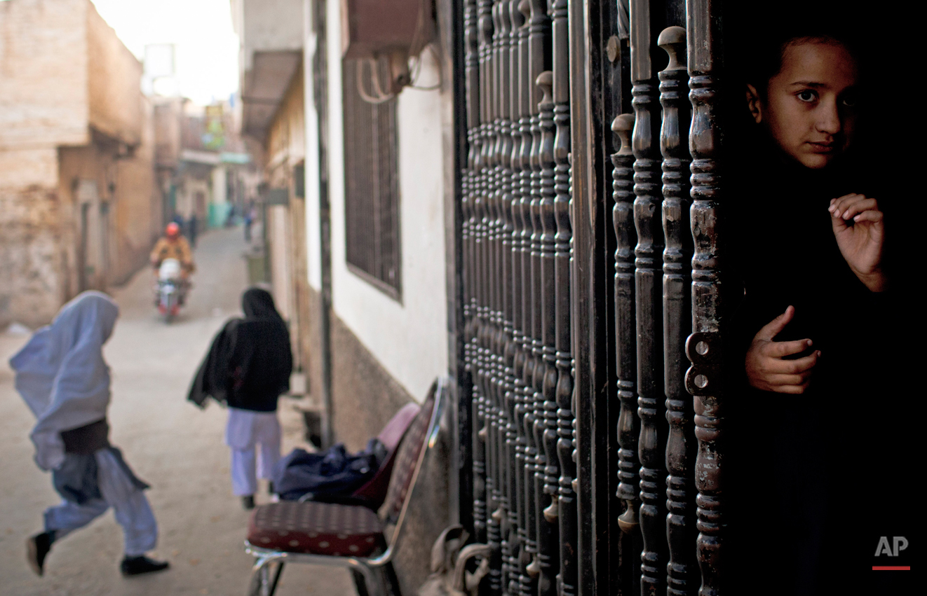  In this Thursday, Nov. 15, 2012 photo, a young girl peeks out from the barred entrance to her school waiting for her fellow students to arrive at Khushal School for Girls in Mingora, Swat Valley Pakistan. Taliban attack survivor Malala Yousafzai of 