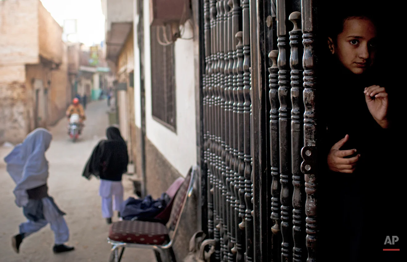 In this Thursday, Nov. 15, 2012 photo, a young girl peeks out from the barred entrance to her school waiting for her fellow students to arrive at Khushal School for Girls in Mingora, Swat Valley Pakistan. Taliban attack survivor Malala Yousafzai of Pakistan won the Nobel Peace Prize on Friday, Oct. 10, 2014, for risking their lives to fight for children's rights. Malala, who moved to Britain for treatment and later settled there, tirelessly continued her campaign for a woman's right to an education in Pakistan and won international recognition for her struggle. But in Pakistan that effort has not stopped as young girls and women struggle to get an education. (AP Photo/Anja Niedringhaus)