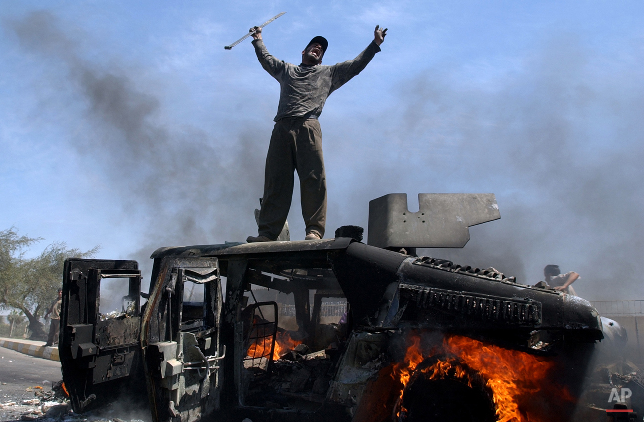  An Iraqi man celebrates atop of a burning U.S. Army Humvee in the northern part of Baghdad, Iraq, Monday, April 26, 2004. An explosion leveled a building in northern Baghdad on Monday, setting four U.S. Humvees nearby on fire. At least one U.S. sold