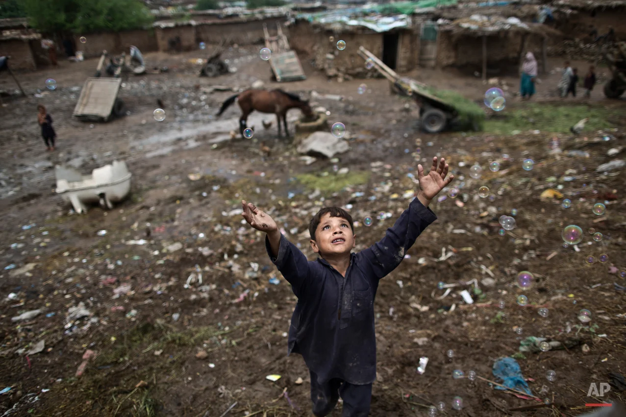 An Afghan refugee child, chases bubbles released by other children, while playing on the outskirts of Islamabad, Pakistan, Friday, Aug. 8, 2014. For more than three decades, Pakistan has been home to one of the world’s largest refugee communities: hundreds of thousands of Afghans who have fled the repeated wars and fighting in their country. Since the 2002 U.S.-led invasion of Afghanistan some 3.8 million Afghans have returned to their home country, according to the U.N.’s refugee agency, but thousands of others still live without electricity, running water and other basic services. (AP Photo/Muhammed Muheisen)