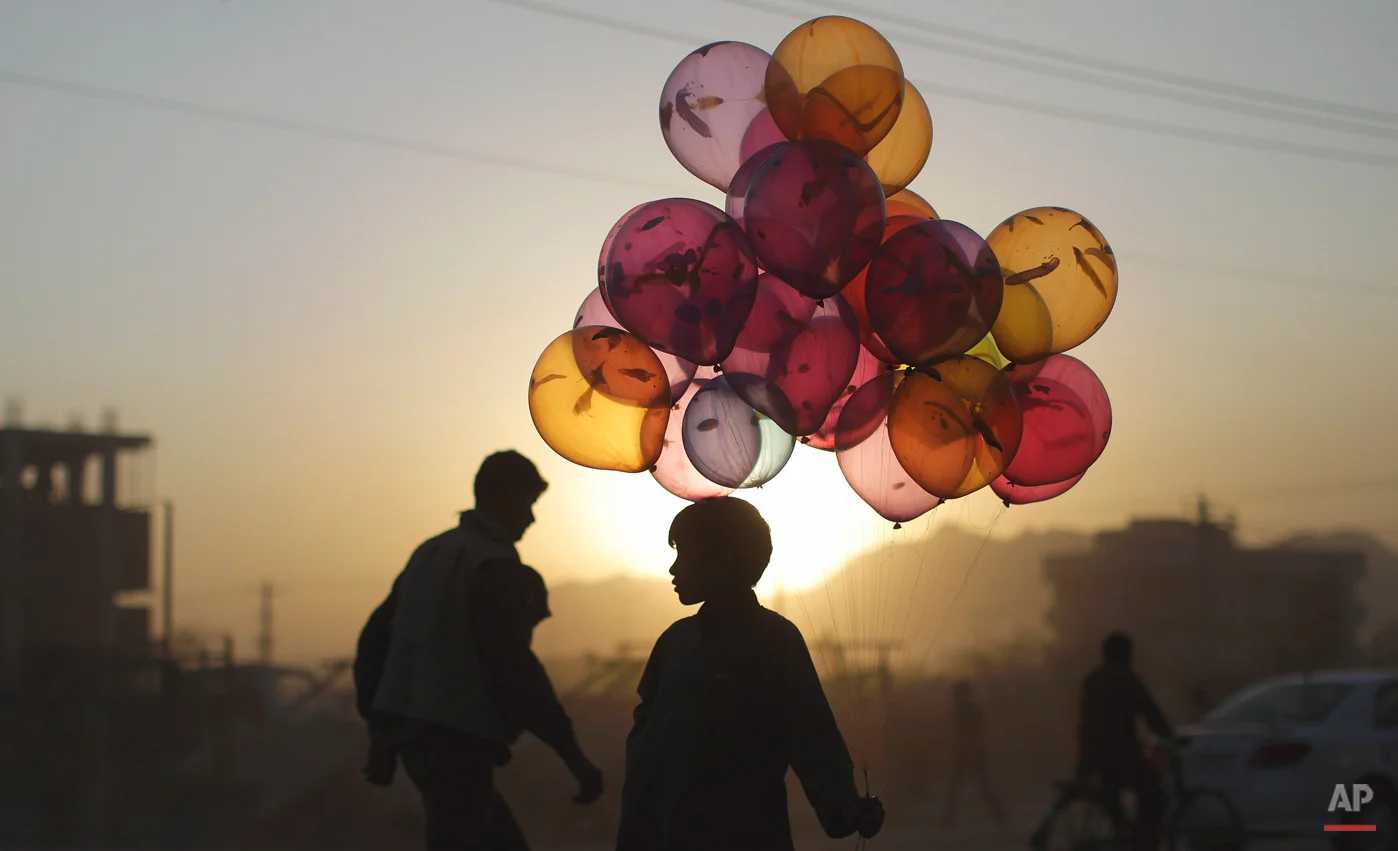 Afghan boy Mahfouz Bahbah, 12, stands on a roadside hoping to sell his balloons during sunset in Kabul, Afghanistan, Tuesday, Oct. 18, 2011. (AP Photo/Muhammed Muheisen)
