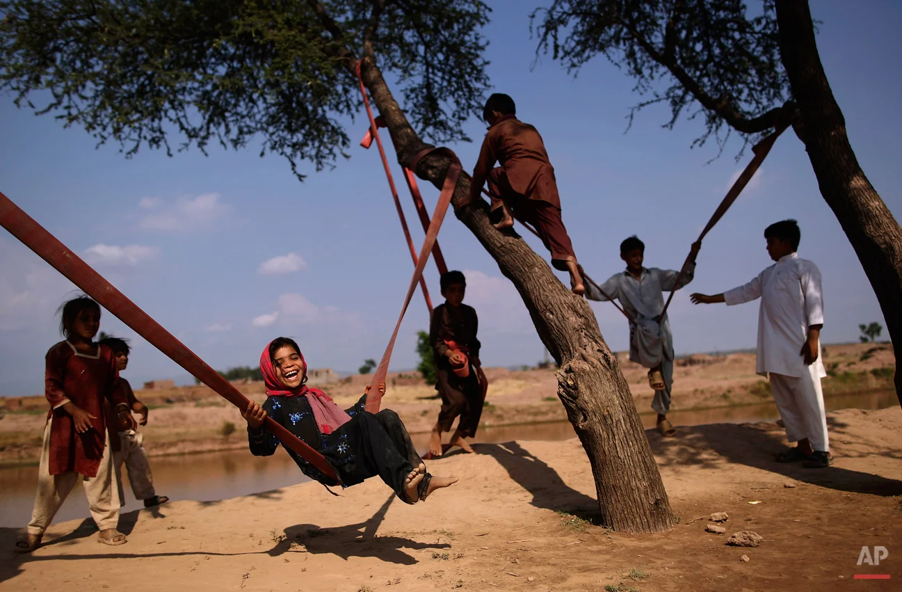 Pakistani Dawlat Gul, 7, third left, enjoys playing on a swing along with other children on the outskirts of Islamabad, Pakistan, Friday, July 13, 2012. (AP Photo/Muhammed Muheisen)