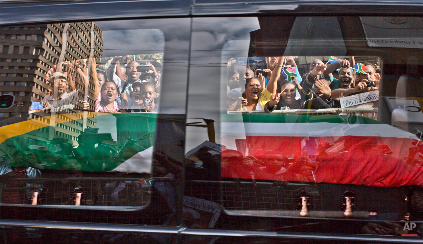 South African mourners, wave and shout as the hearse carrying the body of former South African President Nelson Mandela passes by, in Pretoria, South Africa, Thursday Dec. 12, 2013. (AP Photo/Muhammed Muheisen)