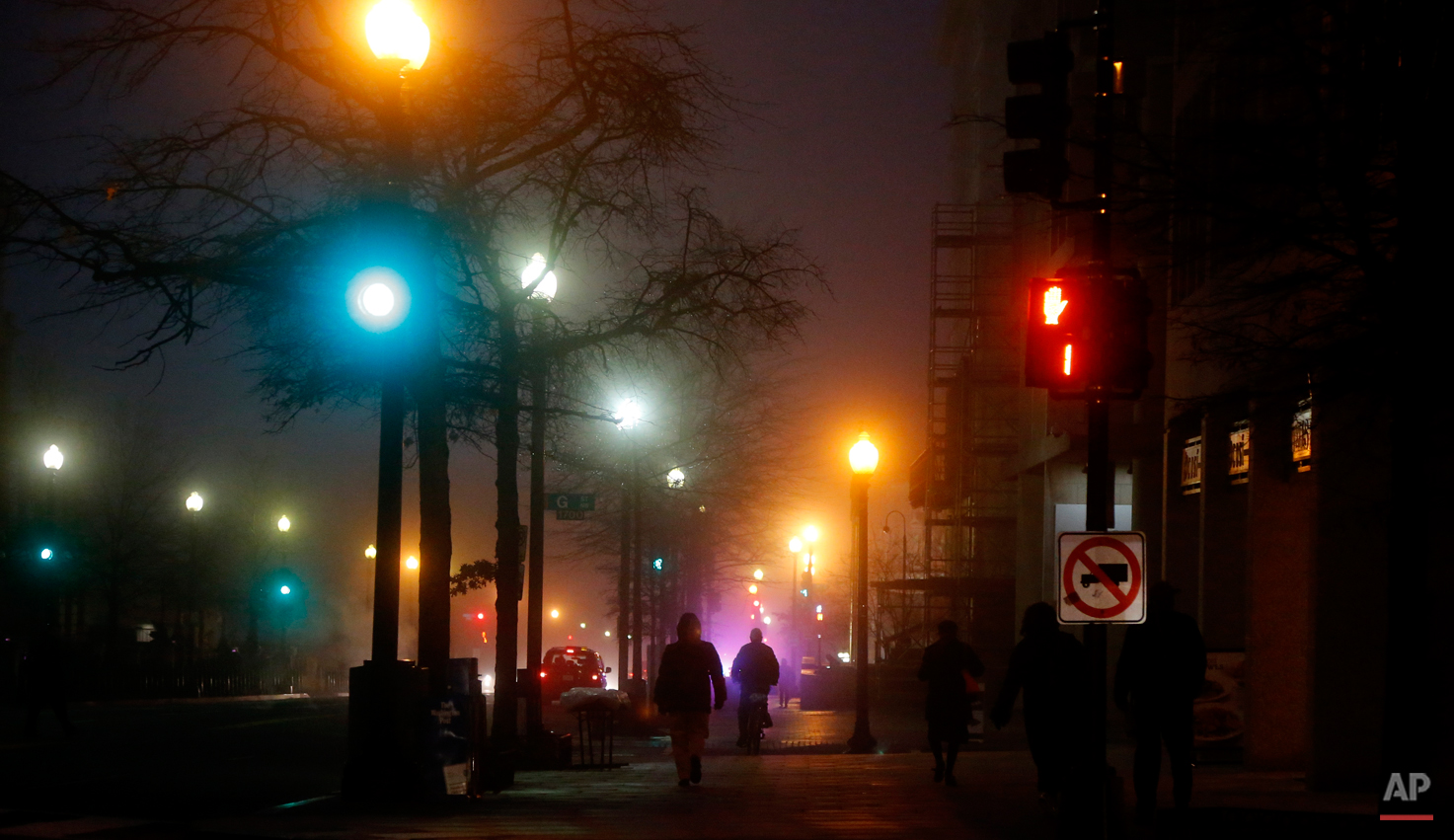  Pedestrians walk in a morning fog on 17th Street and Pennsylvania Avenue NW across from the Eisenhower Executive Office Building in Washington, Wednesday, Jan. 15, 2014. A dense fog has caused limited visibility in the Washington area. (AP Photo/Cha