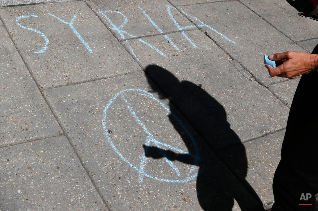  The shadow of Medea Benjamin, founder of CodePink Women for Peace, is seen as she writes Syria and the peace sign in front of the Center for American Progress in Washington, Friday, Sept. 6, 2013,  where US United Nations Ambassador Samantha Power w