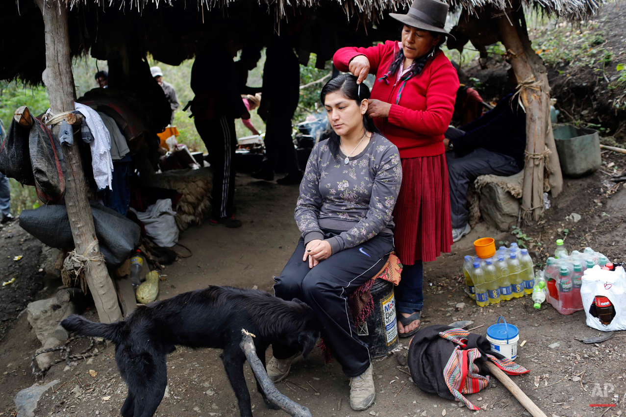  In this Sept. 6, 2014 photo, Dolores Guzman combs archeologist Soledad Mostacero's hair in the Paccha village of Peru. Guzman, sole survivor of a 1984 massacre in Paccha, set aside the street stand where she sells hard-boiled eggs in Lima and journe