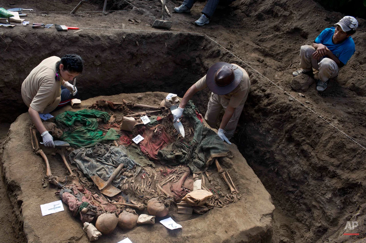 In this Sept. 6, 2014 photo, Eusebio Cuadros, right, watches as forensic anthropologists Soldad Mostacero, left, and Osvaldo Calcina, center right, exhume a mass grave of people slain by security forces, in the Paccha village, in the district of Chungui, Peru. Cuadros' aunt, Natividad, was one of the villagers slain in the July 14, 1984 massacre in Paccha, a hamlet located in the Andean slopes beside the Apurimac river where government forces regularly hunted alleged collaborators of the Maoist guerrillas. (AP Photo/Rodrigo Abd)
